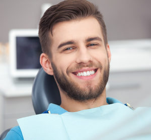 man smiling in dentist chair after root canal treatment